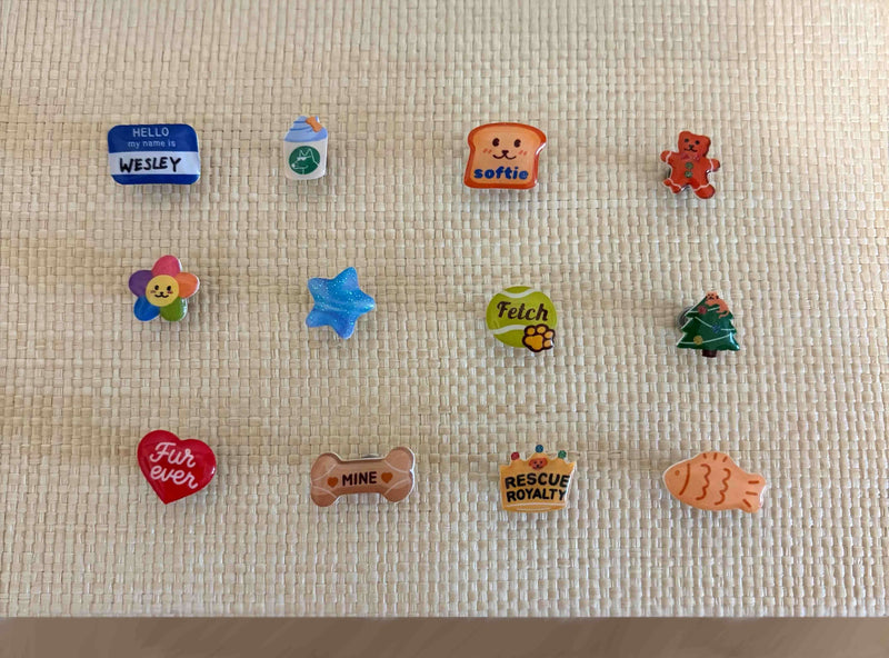 Collection of colorful handcrafted dog collar charms from Pooches & Cream, including heart, bone, star, flower, and bread designs for custom pet accessories.