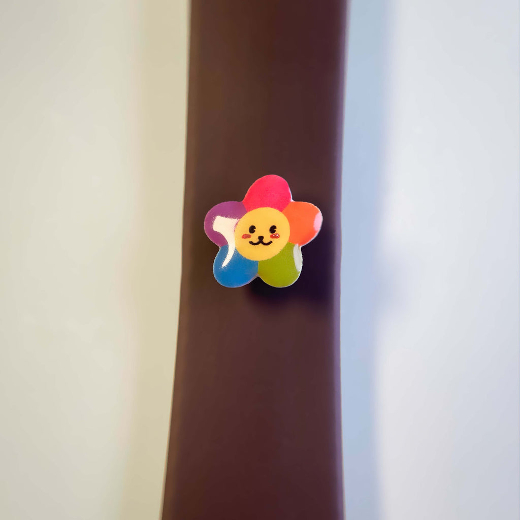 Colorful flower-shaped enamel charm with a smiley face attached to a dog leash.