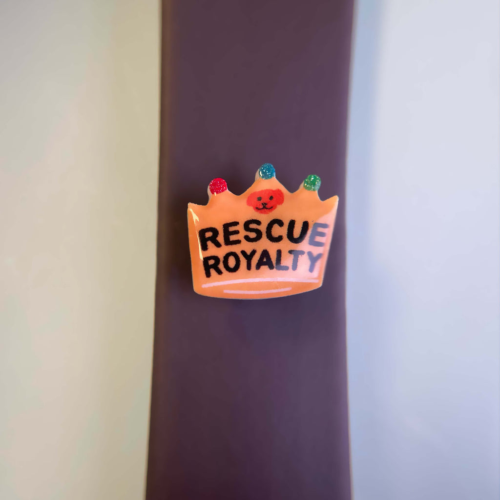 Crown-shaped dog charm with 'Rescue Royalty' text attached to a dog leash.