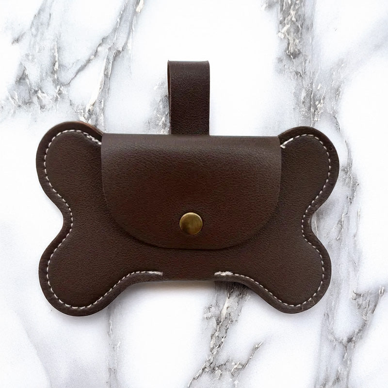 Brown leather bone-shaped dog waste bag dispenser with a gold button.
