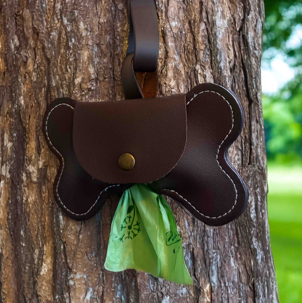 Brown vegan leather dog poop bag holder for leash with green waste bags inside.