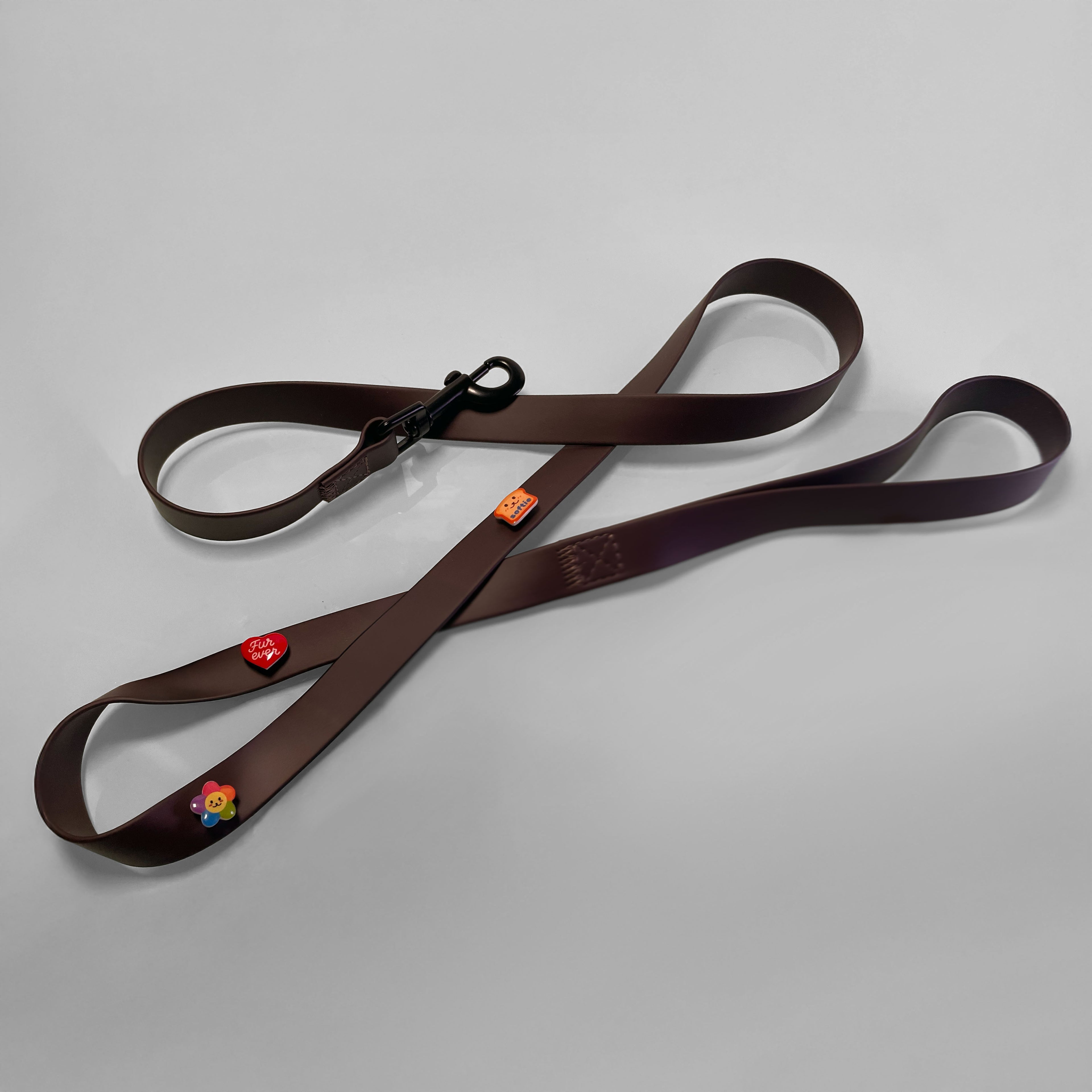 Brown waterproof dog leash with three enamel charms attached.